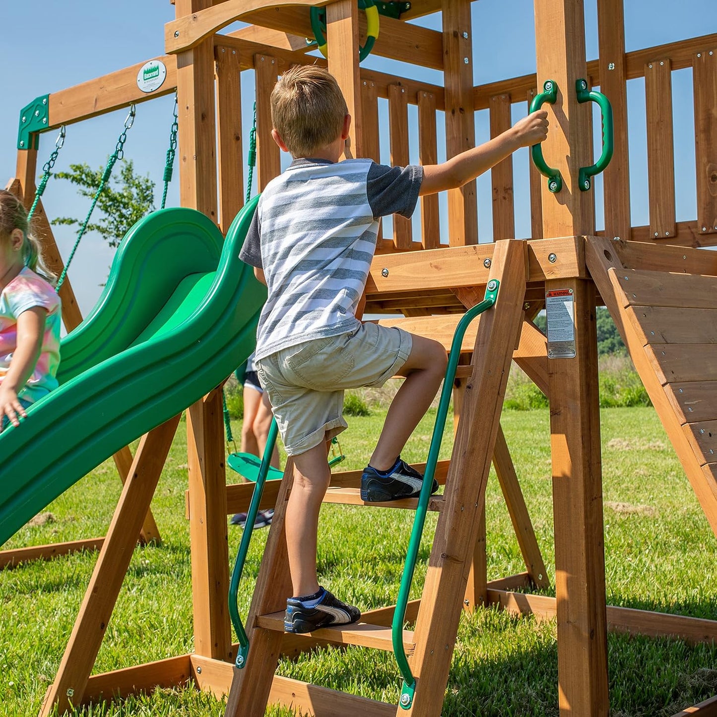 A complete set of wooden mountain-style swings, equipped with a colorful canvas sunshade, a wave slide, a rope swing, a net swing, and a rock wall with climbing ropes and ladders.